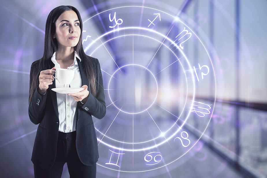 Horoscope concept with woman in black suit with cup of coffee on digital screen background with Zodiac signs
